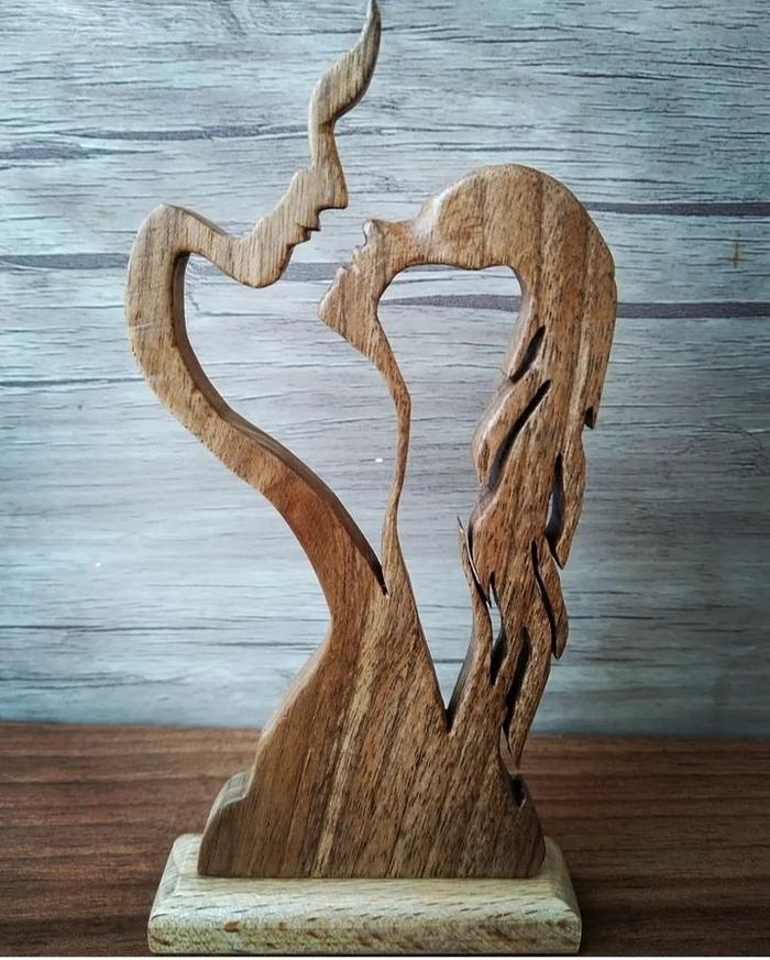 A statue of a man and a woman kissing made of walnut wood